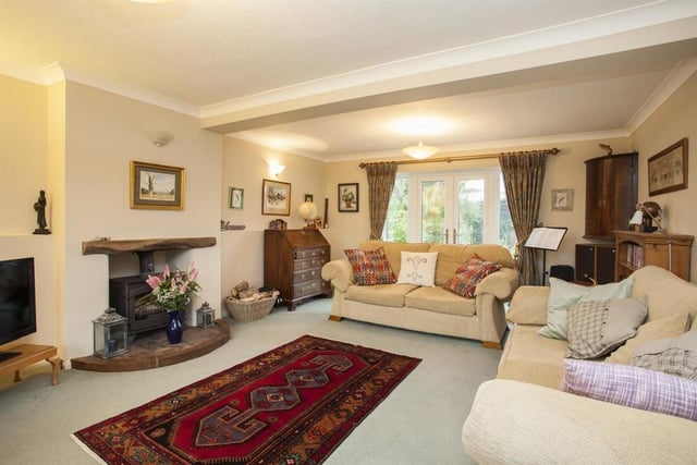 The sitting room, with feature box bay window and French doors opening on to the garden, features an open fireplace with an Aga wood burning stove.