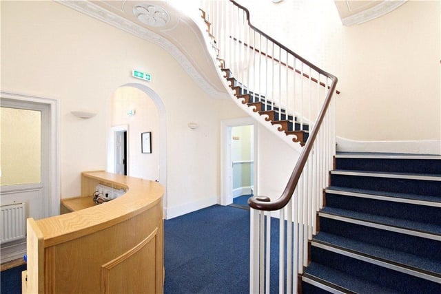The inner hallway, complete with sweeping staircase, currently has a reception desk