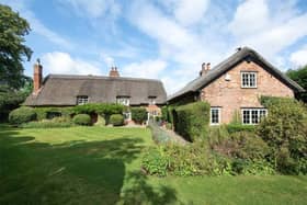 The rear view boasting established gardens leading to lawns and tennis court