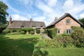The rear view boasting established gardens leading to lawns and tennis court