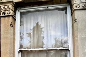 The window to Pauly's flat shows the damp and mould