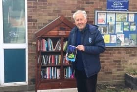 Cllr David Hopkins stacking the shelves of the new library box with a selection of books suitable for all ages