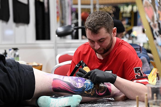 Adding the final touches to a colourful arm tattoo