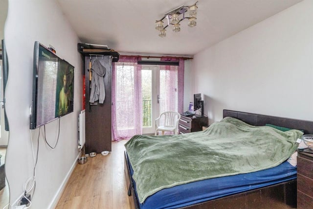 The front bedroom has laminated flooring, a double glazed patio door leading to balcony, and a wall mounted radiator.