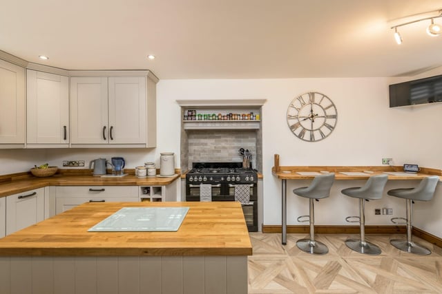 The kitchen breakfast area with range of light grey units, central island and build-in appliances