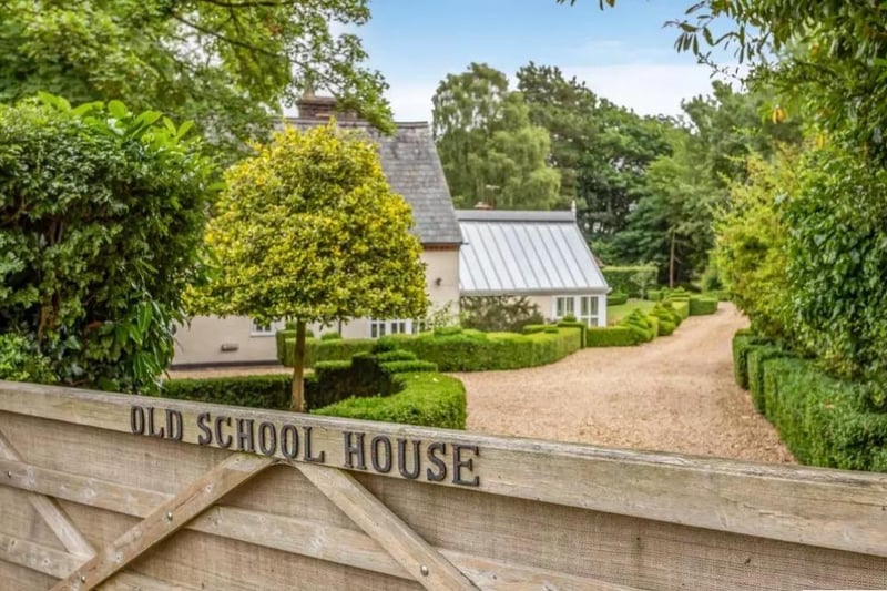 The wooden gates open onto a gravel driveway