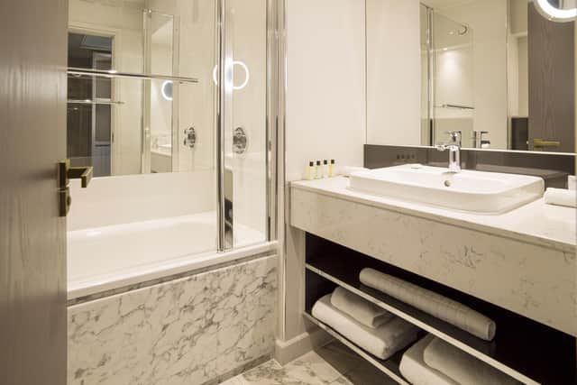 The bathroom is a pretty grey and white marble effect