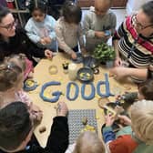 Some nursery practitioners with children making letters spelling ‘GOOD’.