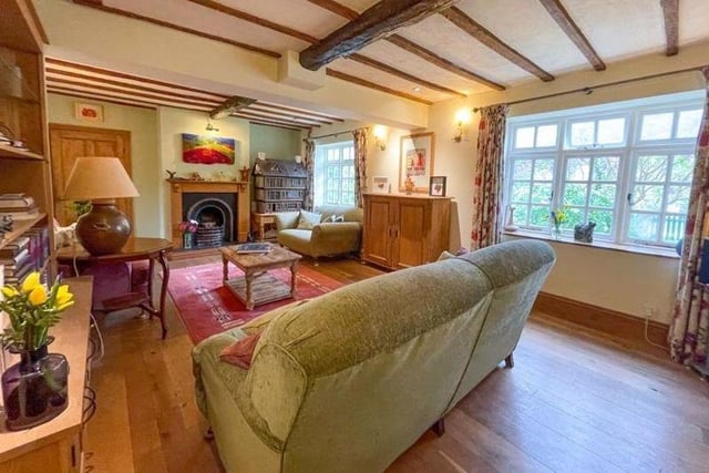 The spacious sitting room boasts exposed beams, feature fireplace and period style Georgian windows