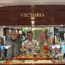 CAMRA members David Martin and John McLaughlin behind the bar with Chris Curtis MP