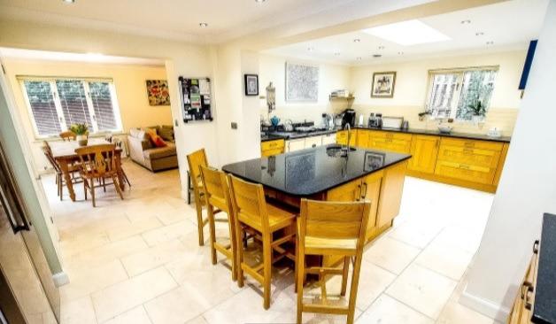 The kitchen contains a large island, granite worktops and integrated appliances.