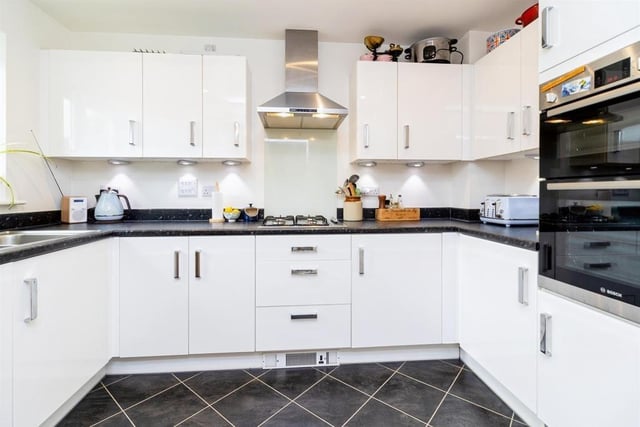 The kitchen features a modern range of wall and base units with ample work surfaces , stainless steel sink, electric oven and gas hob with extractor fan, plus integrated dish washer and fridge/freezer