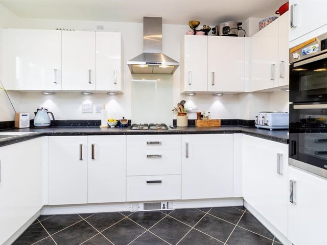 The kitchen features a modern range of wall and base units with ample work surfaces , stainless steel sink, electric oven and gas hob with extractor fan, plus integrated dish washer and fridge/freezer