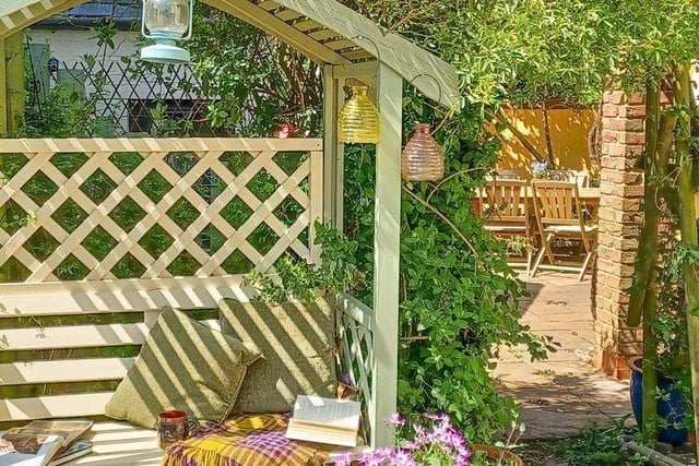 The attractive cottage style garden features an arbour with seating area behind
