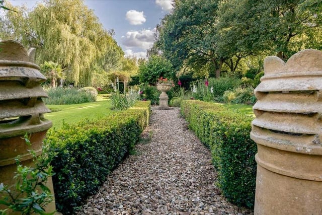 The landscaped gardens feature numerous established plants, shrubs and specimen trees