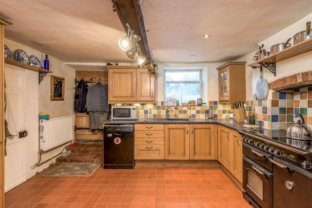 The spacious kitchen is fitted with a range of wooden cabinets with space for a range oven