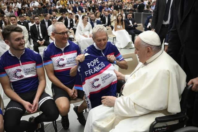Tim Dryburgh and Scott Dryburgh, left and centre, from Milton Keynes, hand over a personalised Cancer Research UK cycling vest to Pope Francis as a thank you for blessing their journey from Rome to London.