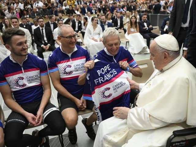 Tim Dryburgh and Scott Dryburgh, left and centre, from Milton Keynes, hand over a personalised Cancer Research UK cycling vest to Pope Francis as a thank you for blessing their journey from Rome to London.