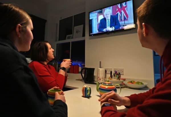 A family gather around the television in Liverpool to watch Britain's Prime Minister Boris Johnson give a televised message to the nation from 10 Downing Street on 4 January (Photo: PAUL ELLIS/AFP via Getty Images)