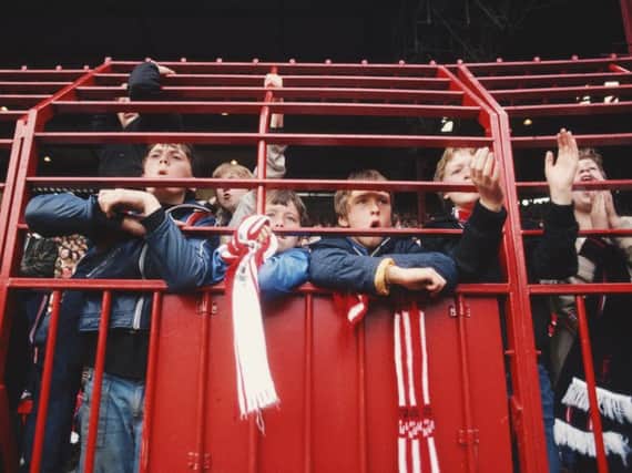 Football fans watching from behind bars during the 1980s