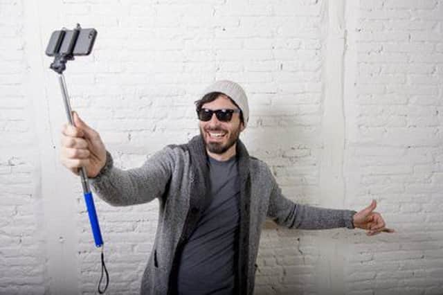 A selfie stick being used to produce a video